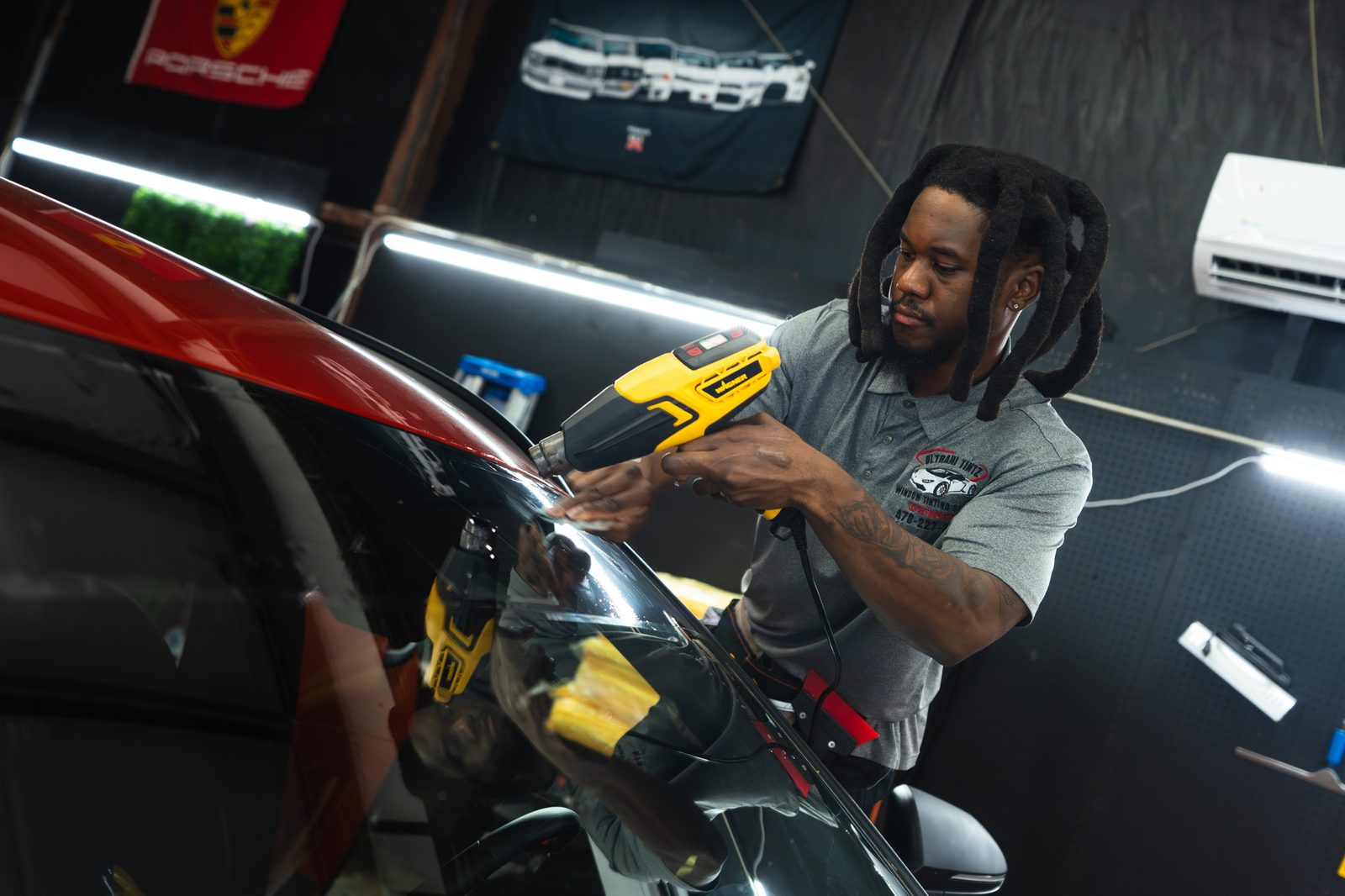 An UltraHI Tintz installer heat-shrinking window film on a car